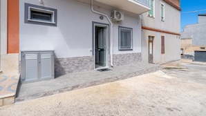 A residential building with a front door, two windows, and an air conditioning unit.