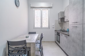 A compact kitchen with a dining table, chairs, and a built-in oven.