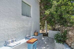 Un edificio blanco con una ventana, una banca y una pequeña mesa.