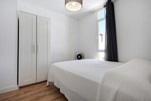 A bedroom with a bed, a wardrobe, a heater, and a window with curtains. - Vacation 'Penthouse 3A' with Sea View, Wi-Fi and Air Conditioning (Morro del Jable)
