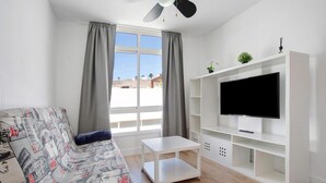 A living room with a sofa, a TV, and a white entertainment unit.