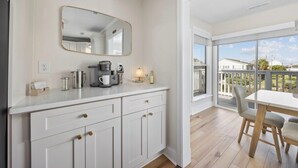 Een moderne keuken met witte kastjes, een koffiezetapparaat en een groot raam.