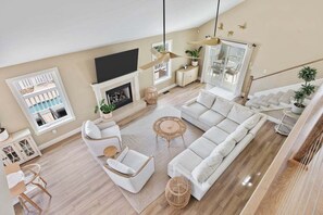 A spacious living room with a large sectional sofa, a fireplace, and a television mounted on the wall.