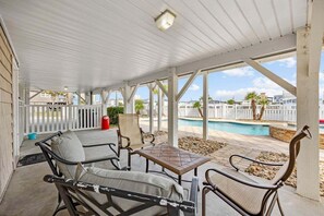 A covered patio area with outdoor furniture, a pool, and a view of the surrounding neighborhood.