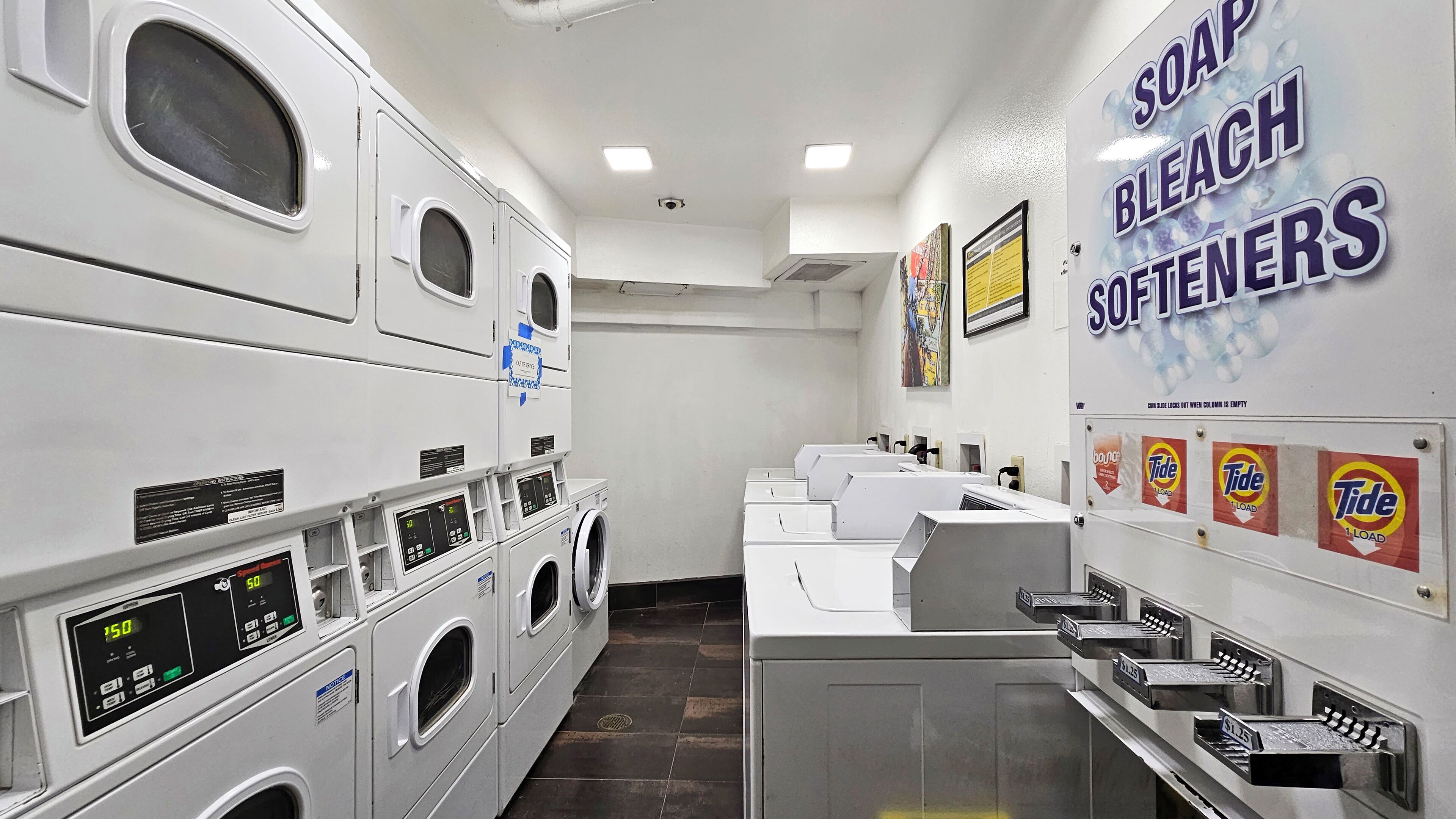 A laundromat with multiple washing machines, dryers, and Tide detergent dispensers.