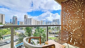 A balcony with a view of a cityscape, including tall buildings and palm trees.