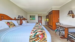 A hotel room with two beds, a desk, a chair, a dining area, and a kitchen.