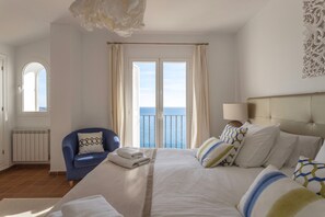Une chambre d’hôtel avec un lit, une chaise, une vue sur la mer et un radiateur.