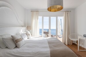 Une chambre à coucher avec un lit, un bureau, une chaise et une vue sur la mer.