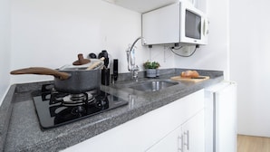 A modern kitchen with a gas stove, a microwave, and a sink. - AC, vaga, academia Vila Olímpia | Brazilian Corner (Sao Paulo)