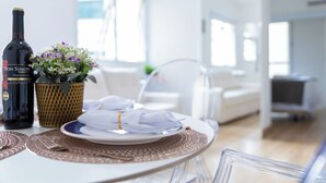 A dining table set with a bottle of wine, a woven basket with flowers, and a plate with a folded napkin. - AC, vaga, academia Vila Olímpia | Brazilian Corner (Sao Paulo)