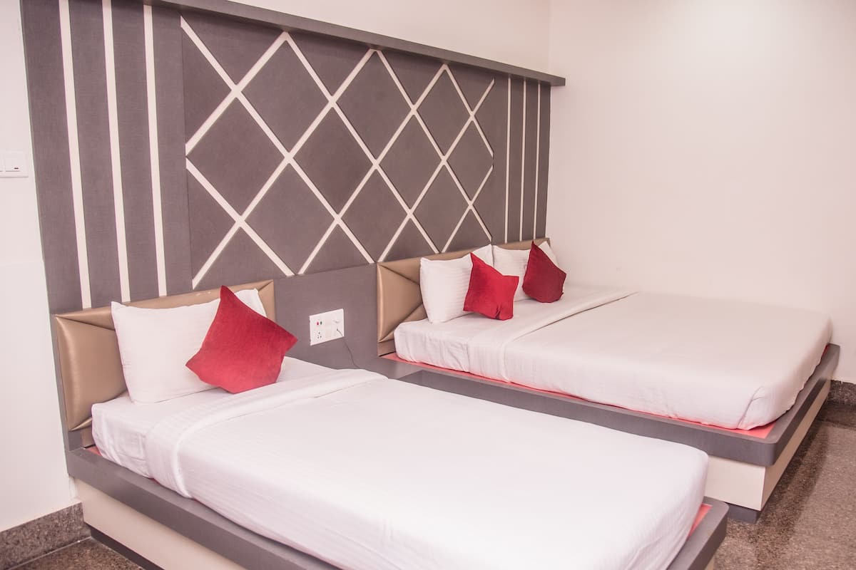 Two single beds with headboards, white bedding, and red pillows in a room with a geometric-patterned headboard.