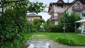 A residential area with a paved pathway, greenery, and houses with balconies.