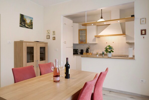 Un coin repas avec une table en bois, des chaises rouges et une bouteille de vin.