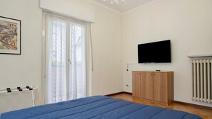 A bedroom with a bed, a TV, a wardrobe, and a radiator.