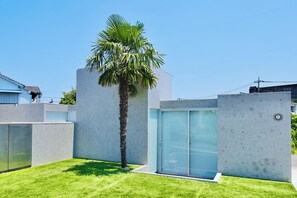 Un bâtiment moderne avec un palmier, une porte de garage et un mur en béton.