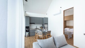 A modern apartment with a dining area, kitchenette, and a bedroom.