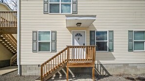 Ein zweistöckiges Haus mit Veranda, Treppe und einer Tür mit der Aufschrift '10B'.