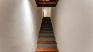 A narrow stairway with a wooden ceiling and a white wall.