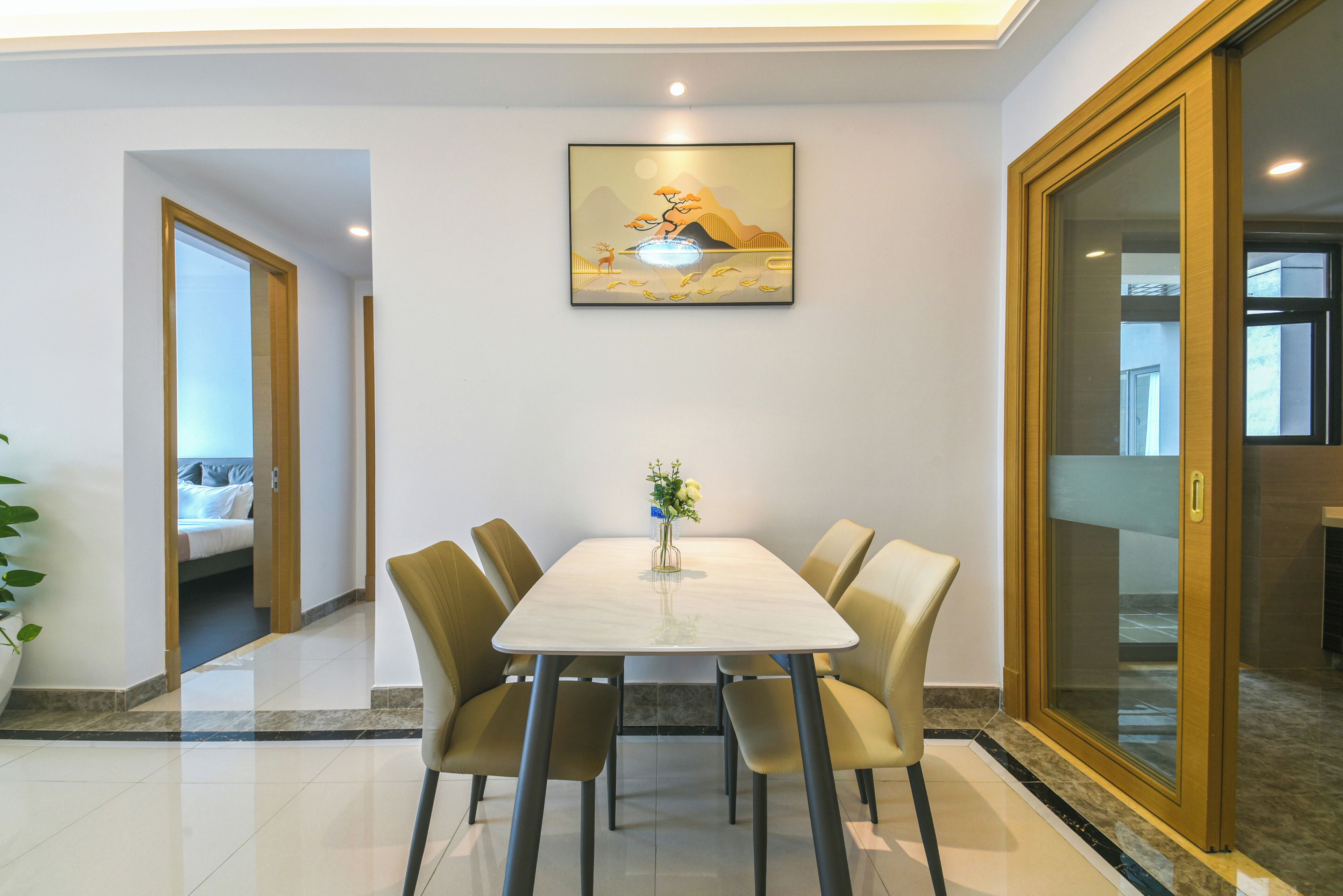 A dining area with a white table, four chairs, and a vase with flowers.