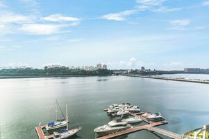 A marina with several boats docked, a clear sky, and a cityscape in the background.