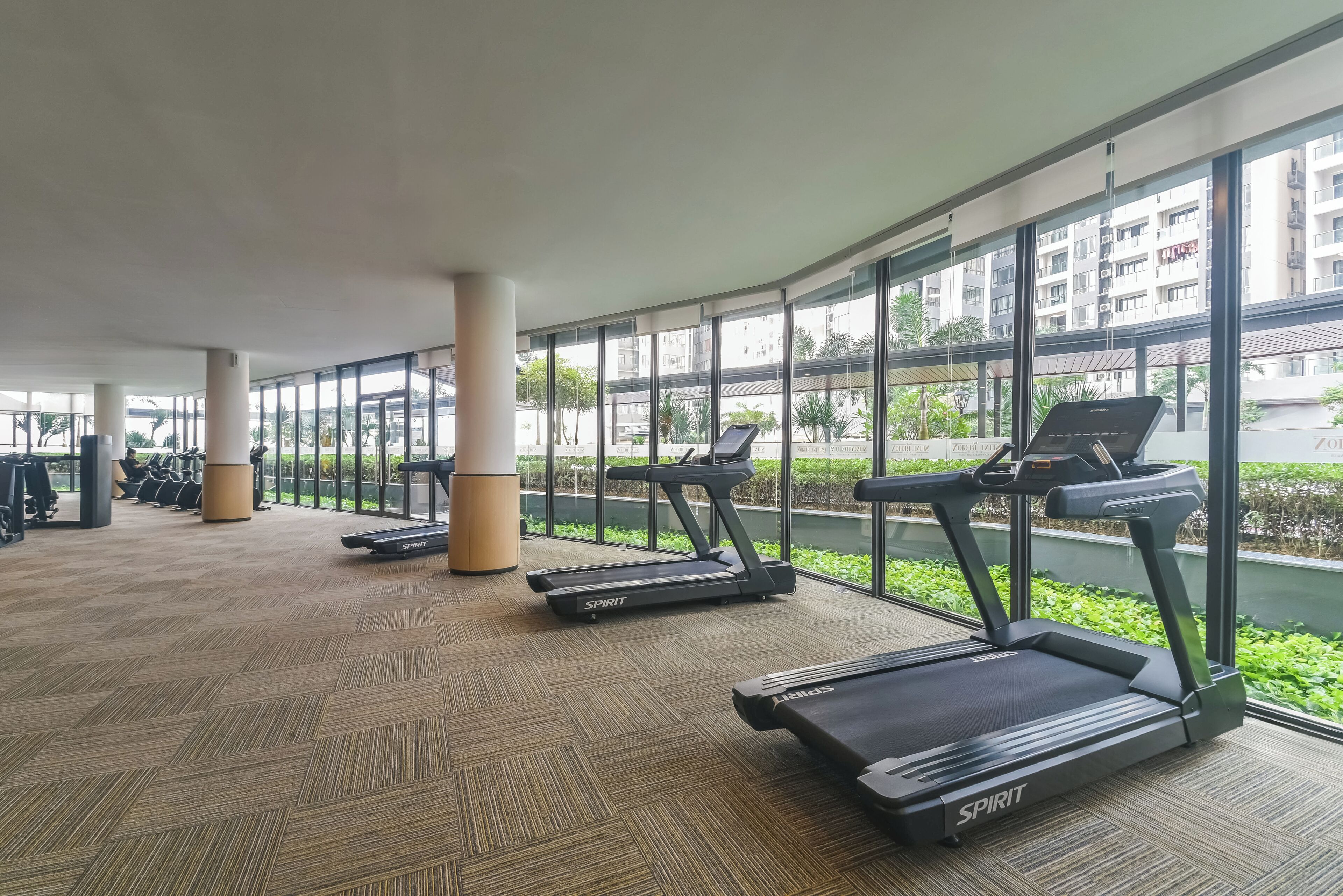Un gimnasio con cintas de correr, bicicletas estáticas y un amplio ventanal con vistas a la ciudad.