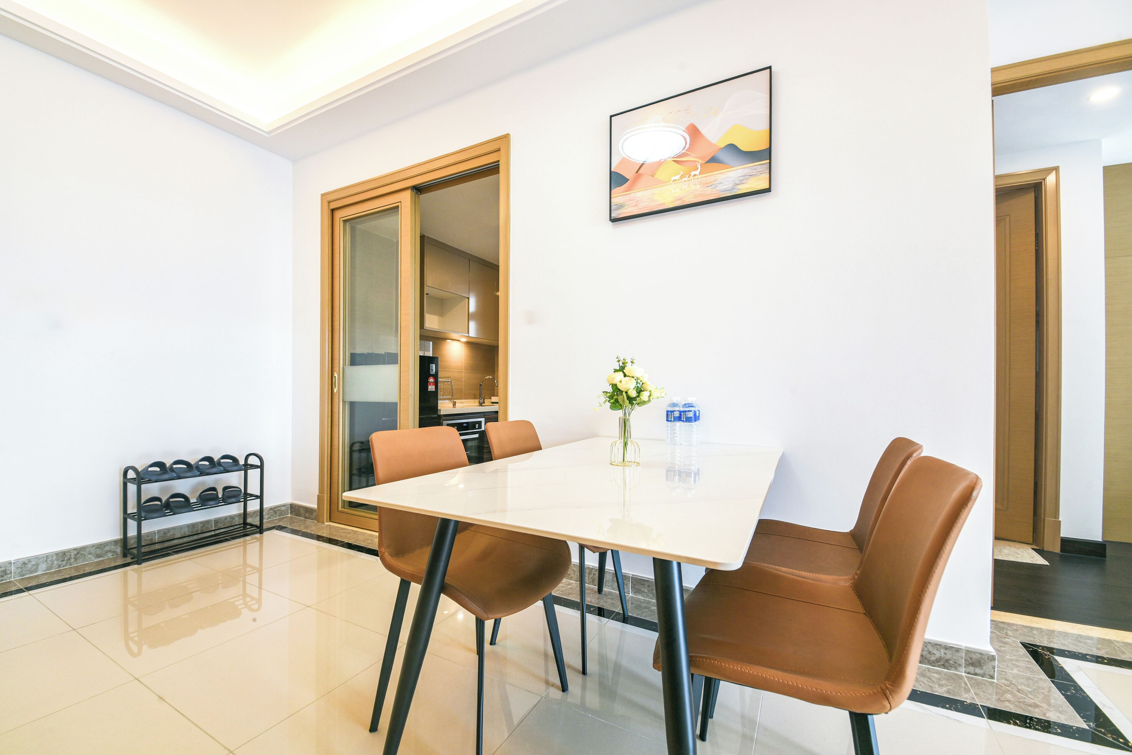 A dining area with a white table, brown chairs, a vase with flowers, and a rack of bottles.