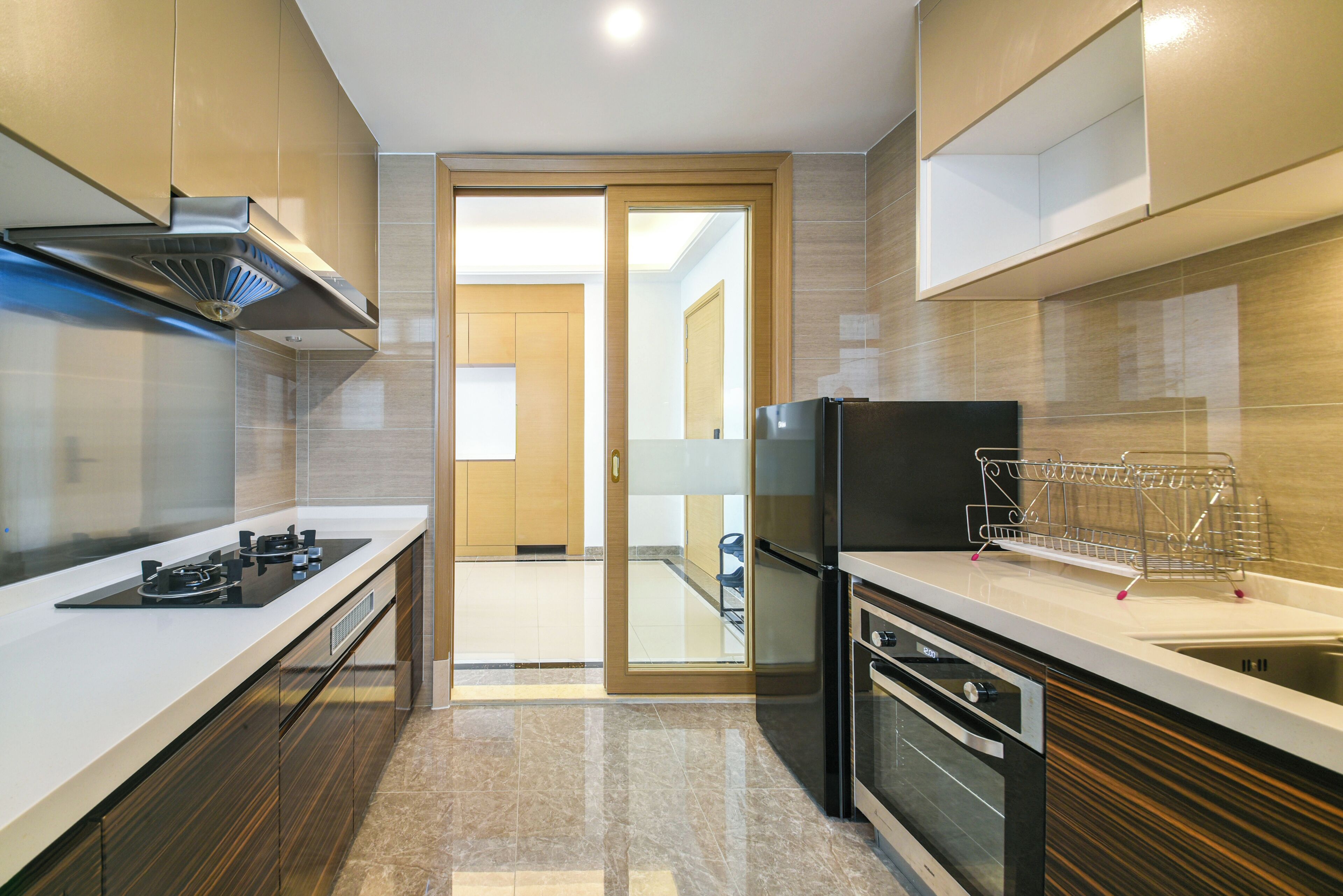 A modern kitchen with a gas stove, oven, and built-in microwave. There is a wooden door leading to another room.