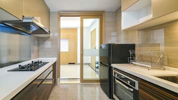 A modern kitchen with a gas stove, oven, and built-in microwave. There is a wooden door leading to another room.