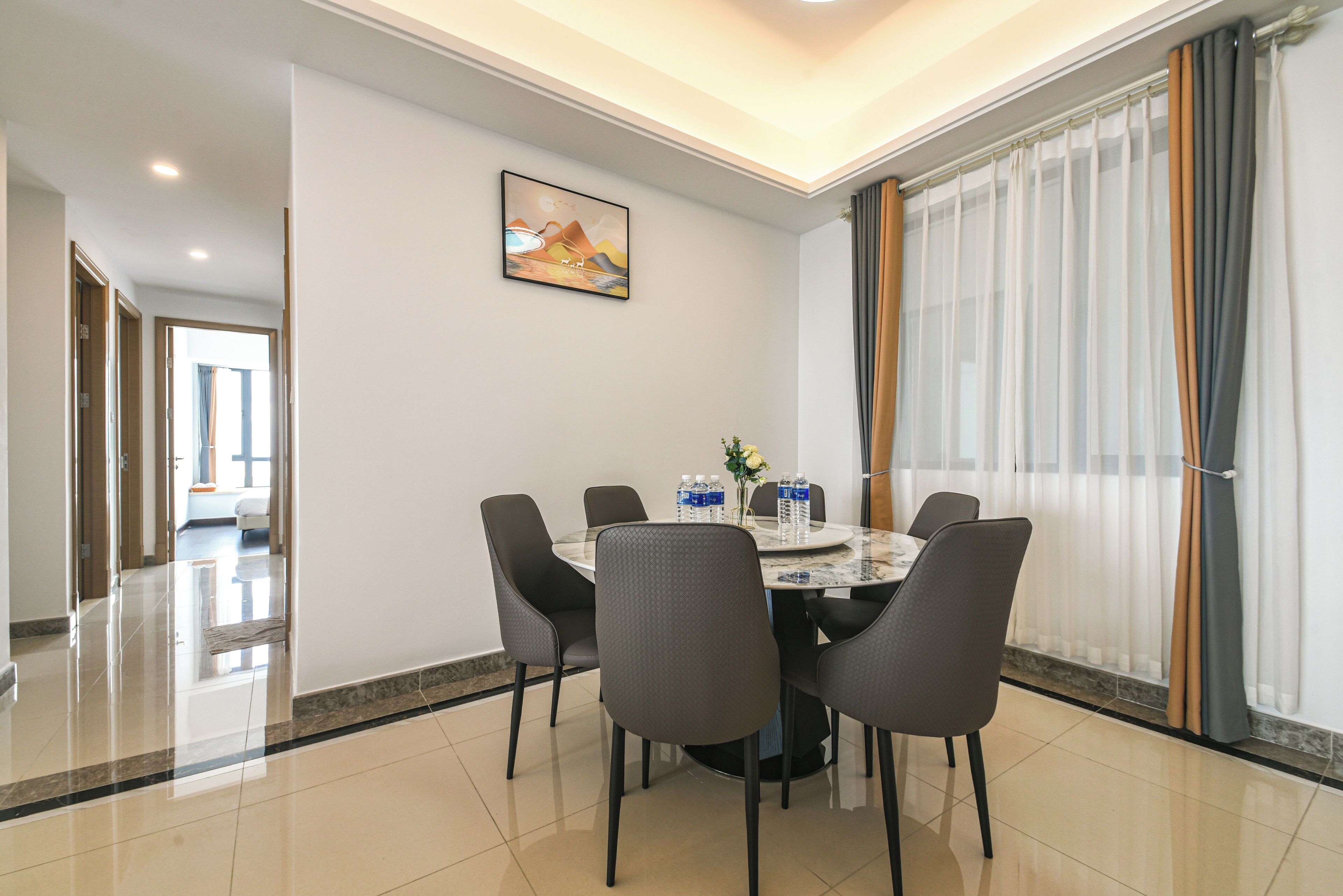 A dining area with a round table, six chairs, and a vase with flowers.