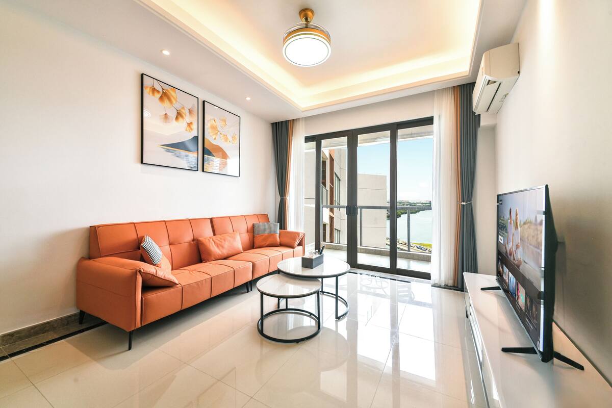A modern living room with a sofa, a coffee table, and a flat-screen TV.