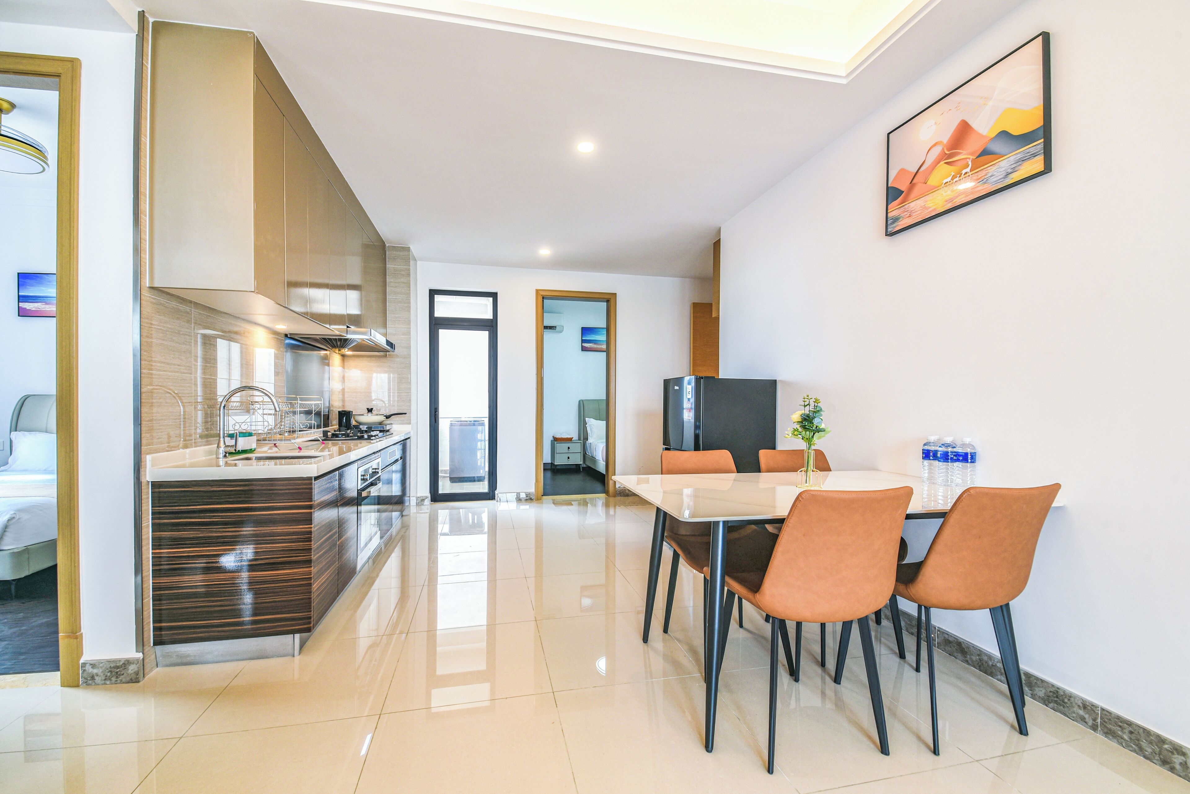 A modern kitchen with a built-in oven, a dining area with a table and chairs, and a large window.