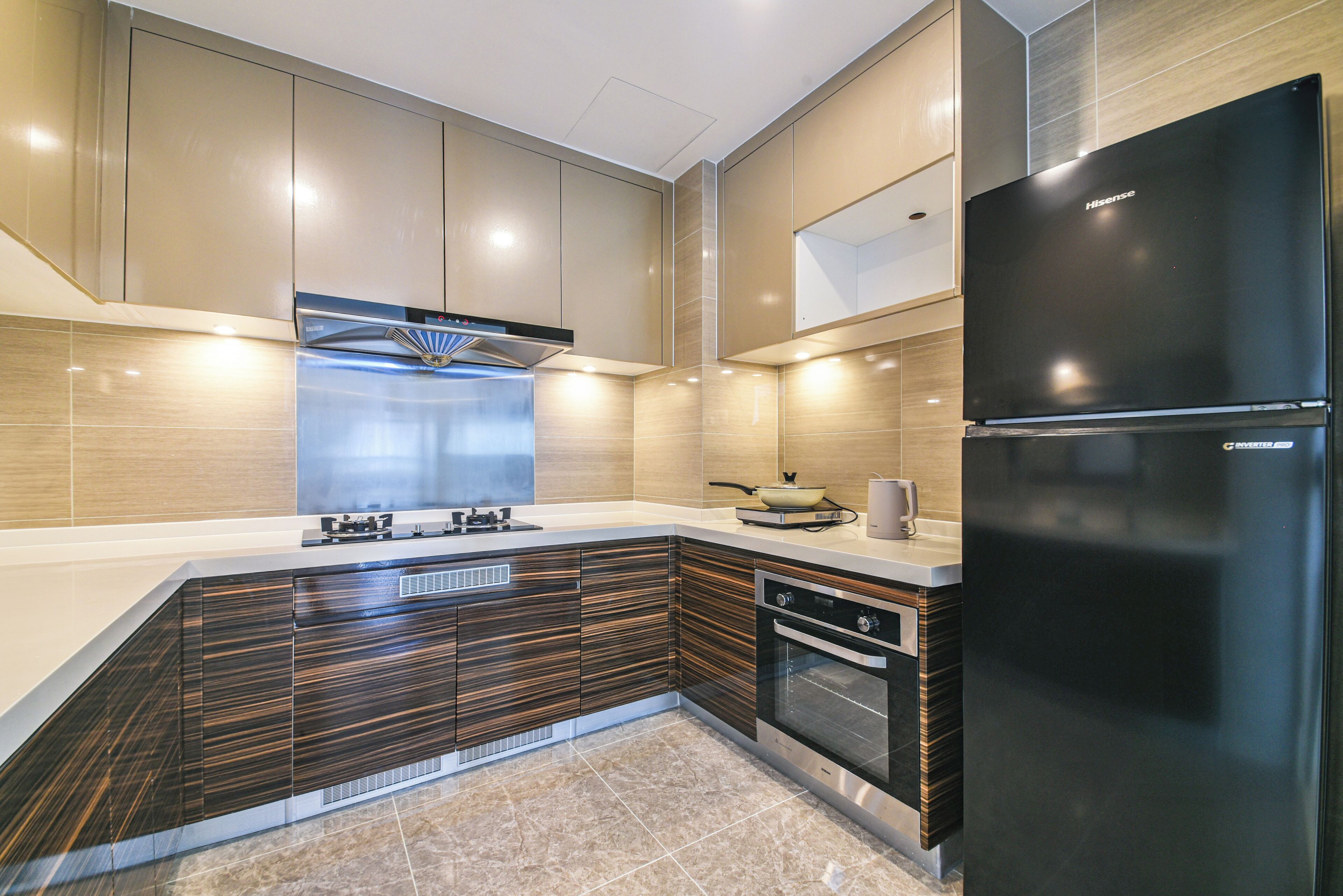 A modern kitchen with a black refrigerator, stainless steel appliances, and wooden cabinetry.