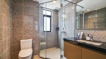 A modern bathroom with a glass-enclosed shower, a toilet, and a vanity with a mirror.
