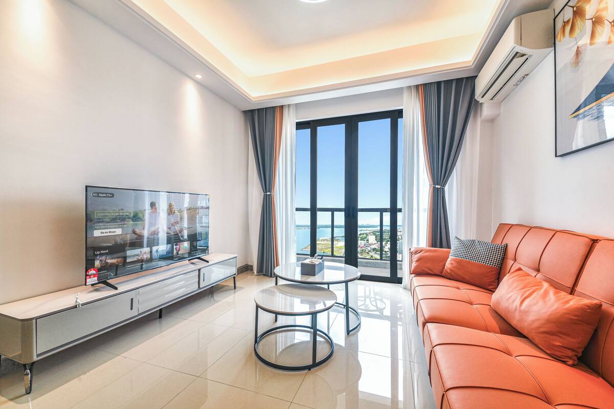 A modern living room with a sofa, a coffee table, and a TV on a stand.