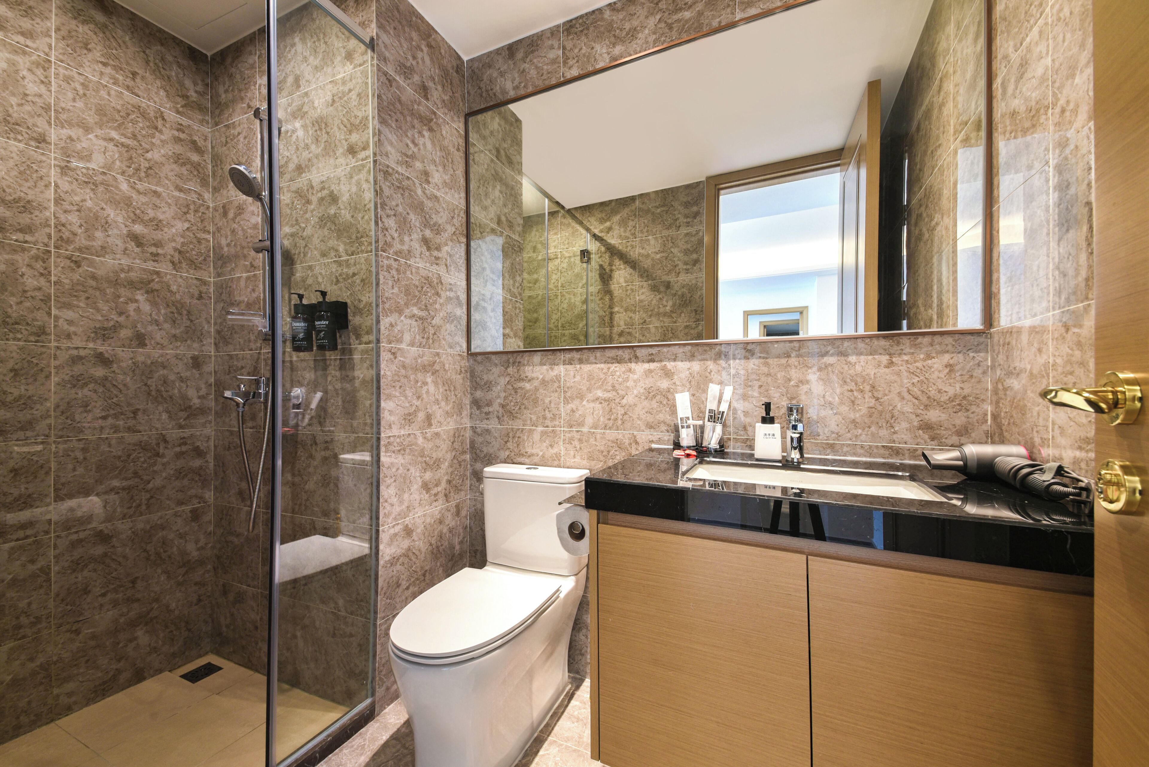 A modern bathroom with a glass-enclosed shower, a toilet, and a vanity with a sink and mirror.