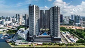 Un edificio de gran altura con varios pisos, piscina y un puerto deportivo con barcos.