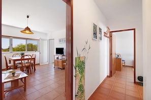 Um quarto espaçoso com área de refeições, televisão e uma grande janela.