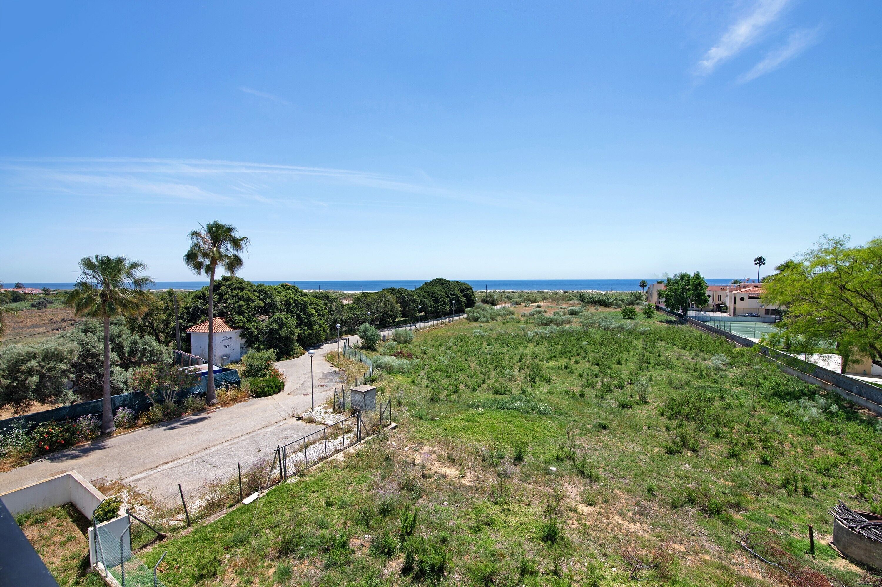 Un barrio residencial con una calle, una propiedad cercada y vista al mar.