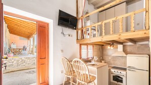 Une cuisine compacte avec un coin repas en bois, un four encastré et un téléviseur fixé au mur.