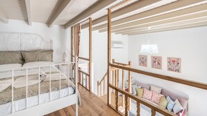 Une chambre avec un lit superposé, un escalier en bois et un canapé agrémenté de coussins à motifs.