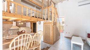 Une cuisine moderne agrémentée d’éléments en bois, un coin repas avec des chaises, une petite table et un escalier menant à un niveau supérieur.