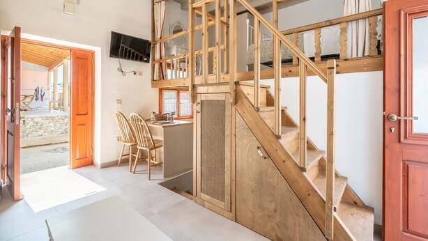 Un escalier en bois mène à une mezzanine où est fixé un téléviseur au mur.