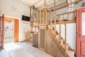 A wooden staircase leading to a loft area with a TV mounted on the wall.