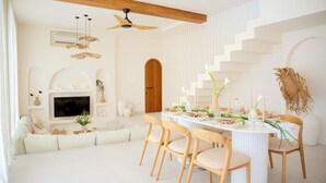 Ein modernes Wohnzimmer mit Essbereich, einer Couch, einem Fernseher und einer Treppe.