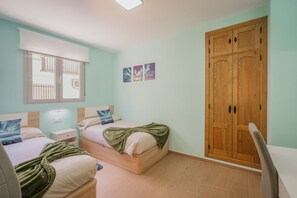 A bedroom with two beds, a wooden wardrobe, a window with blinds, and a small bedside table with a lamp. - Apartment 'La Aurora De Candeleda' with Lake View, Wi-Fi and Air Conditioning (Candeleda)