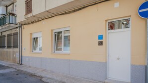 Un edificio con facciata gialla, una porta bianca e una finestra con inferriata metallica.