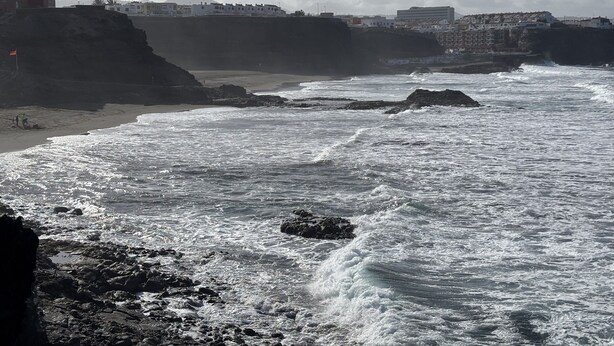 A coastal scene with rocky terrain, waves, and buildings in the background. - Casa 'Discover the Sea' Vacation Home with Private Terrace and Wi-Fi (La Garita)