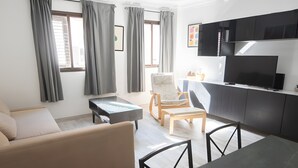 A modern living room with a sofa, a dining table, a TV, and a kitchen area. - Casa 'Discover the Sea' Vacation Home with Private Terrace and Wi-Fi (La Garita)