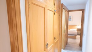 A hallway with wooden wardrobes, a bed with a white mattress, and a nightstand with a lamp. - Casa 'Discover the Sea' Vacation Home with Private Terrace and Wi-Fi (La Garita)